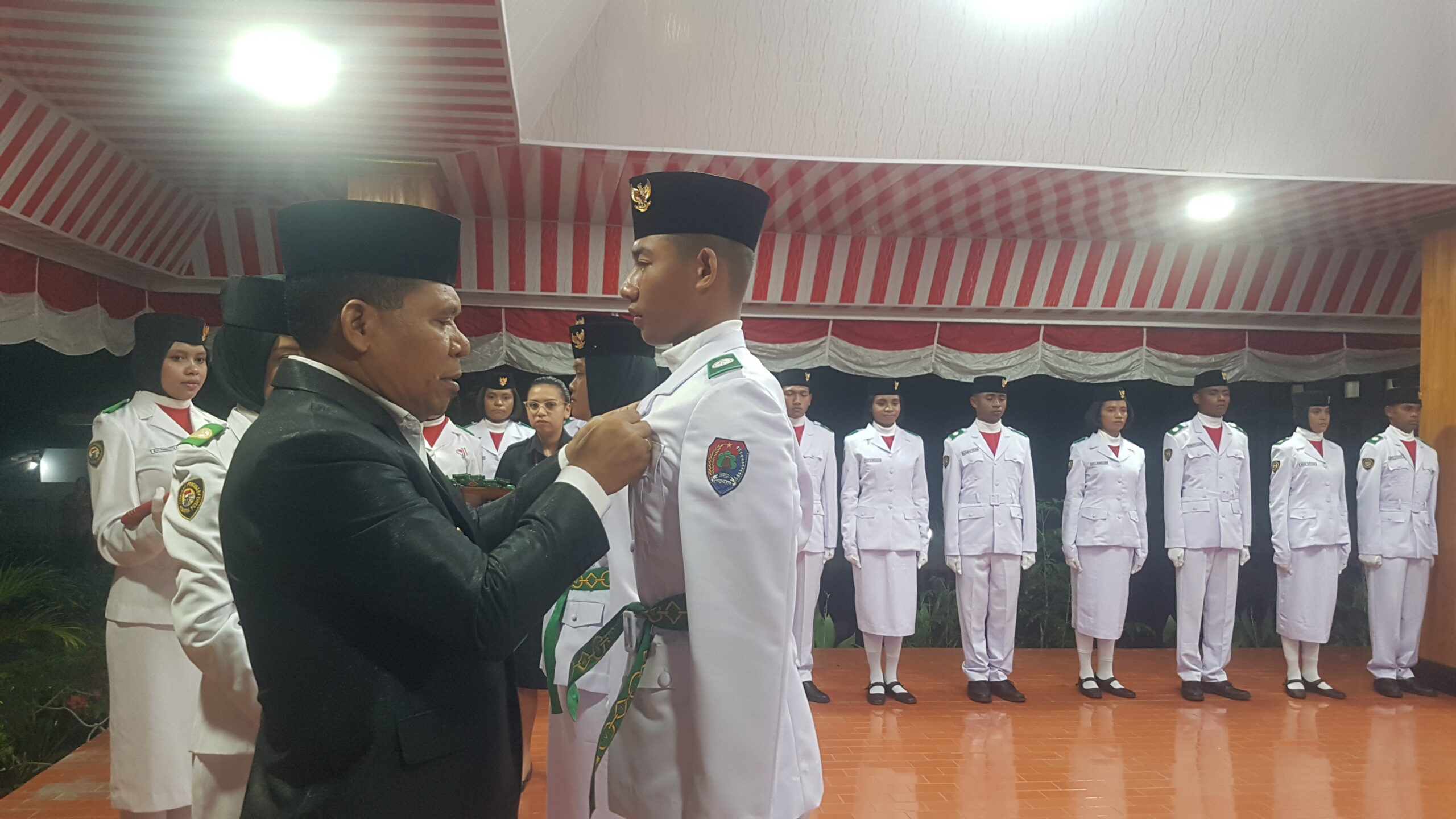 Pj. Bupati Alor Dr. Drs. Zet Sony Libing, M.Si memasang lencana kepada salah seorang anggota PASKIBRAKA Kabupaten Alor 2024 setelah dilakukan pengukuhan. FOTO:MORISWENI/radarpantar.com