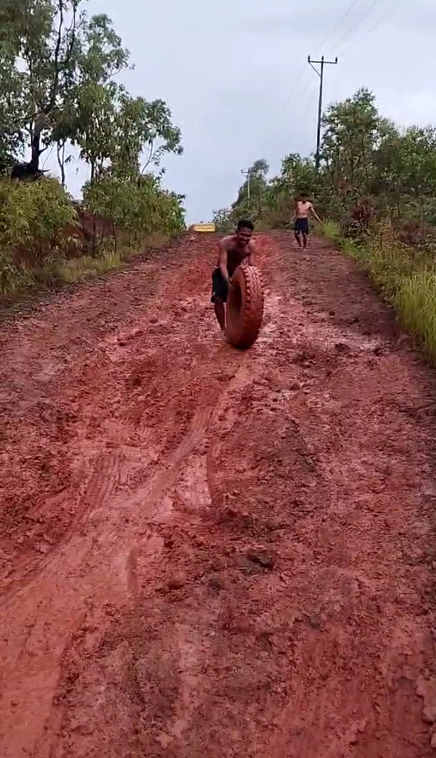 Akses jalan berlumpur, mengandung tanah merah seperti ini yang menyulitkan kendaraan (truk) mengangkut material non lokal menuju lokasi pekerjaan di Desa Manetwati. Nampak salah seorang anak buah truk menggiring roda mobil untuk mengganti ban truk yang jebol saat mengangkut metrial ke lokasi proyek. FOTO:DOK